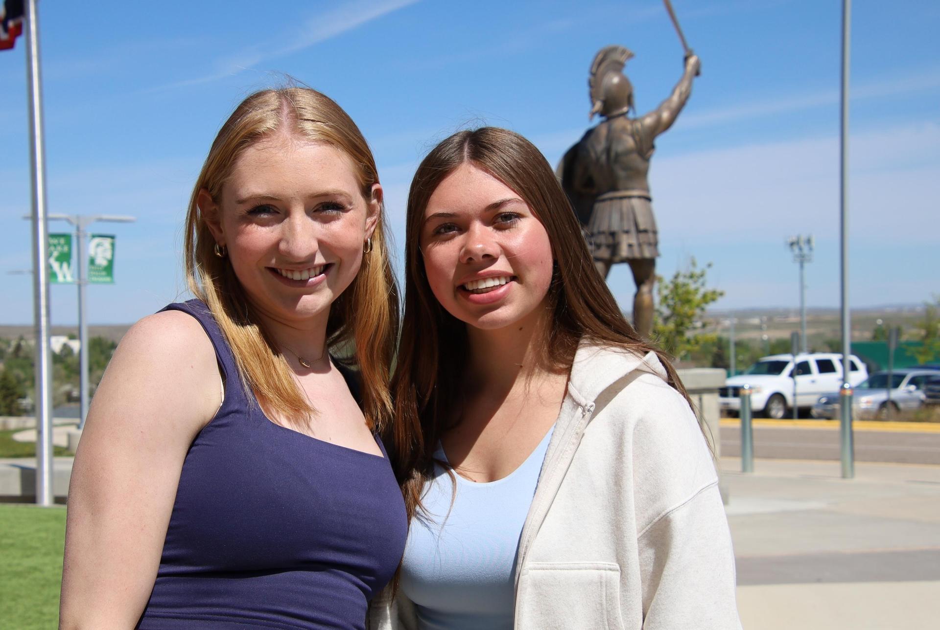 high school girls smiling at the camera outside of a school