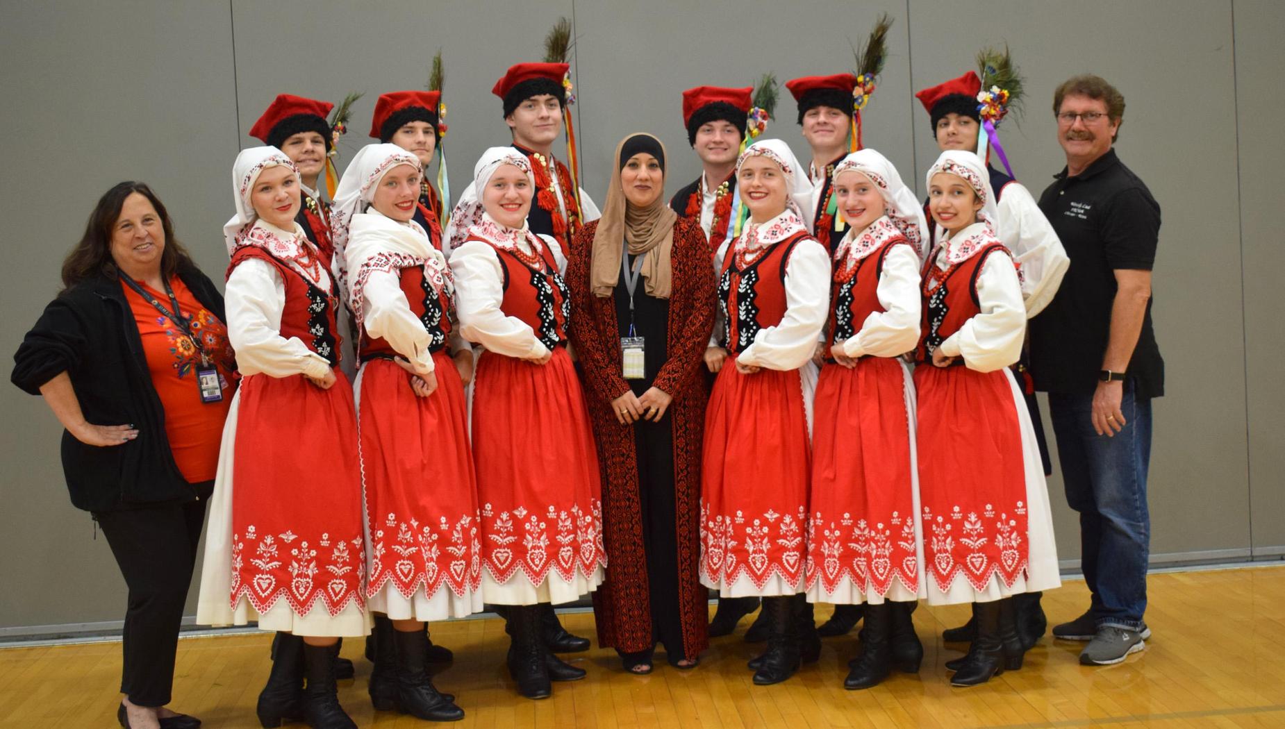 Group of traditional dancers in colorful costumes posing together indoors.