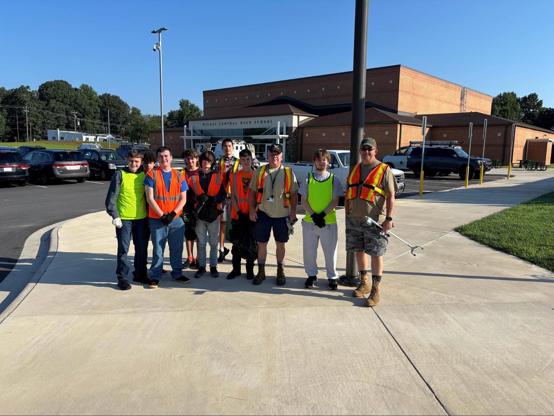 A group of volunteers poses in safety vests outside a school building.