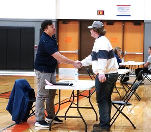 A student greets his interviewer with a handshake.