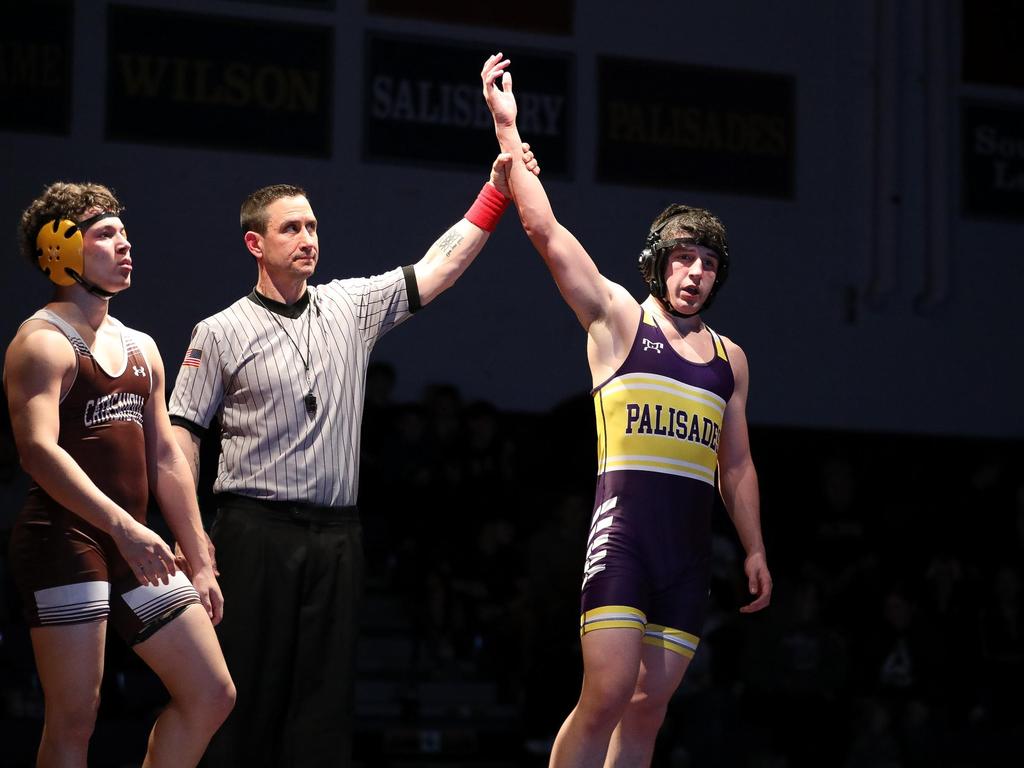 A referee holds up the arm of a winning wrestler.