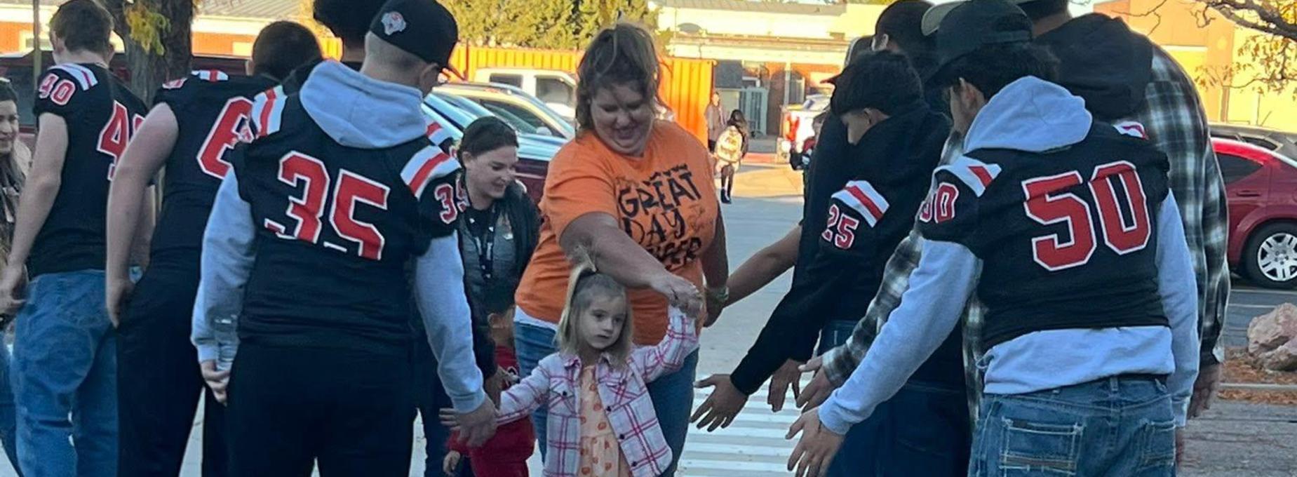 A group of people reaching out to a child crossing a sidewalk.