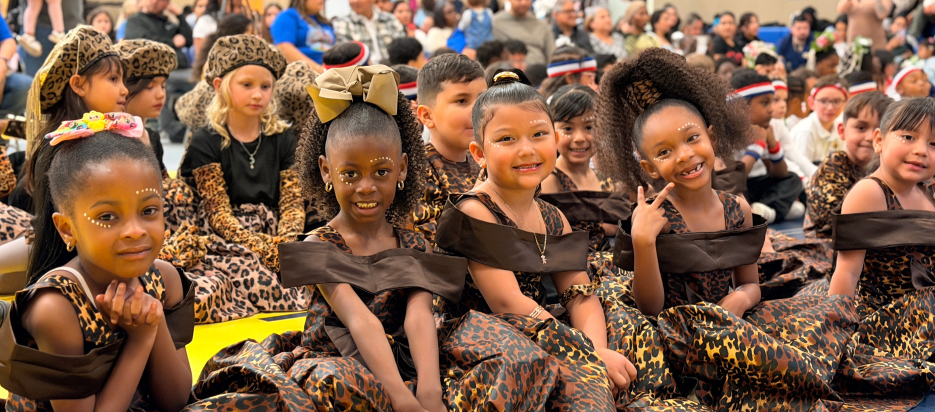 Children in leopard-print costumes smiling during a performance.