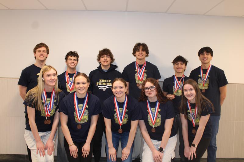 group of swimmers with swim shirts on and medals around their neck