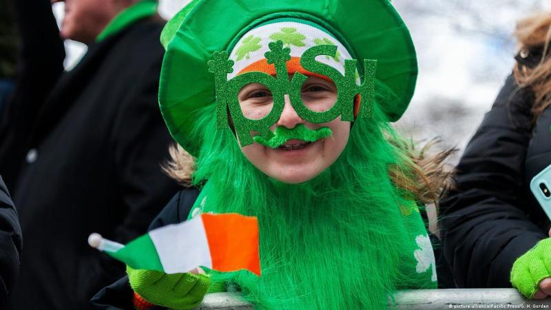 Child celebrating St. Patrick's Day wearing green attire, oversized glasses, and a shamrock beard.