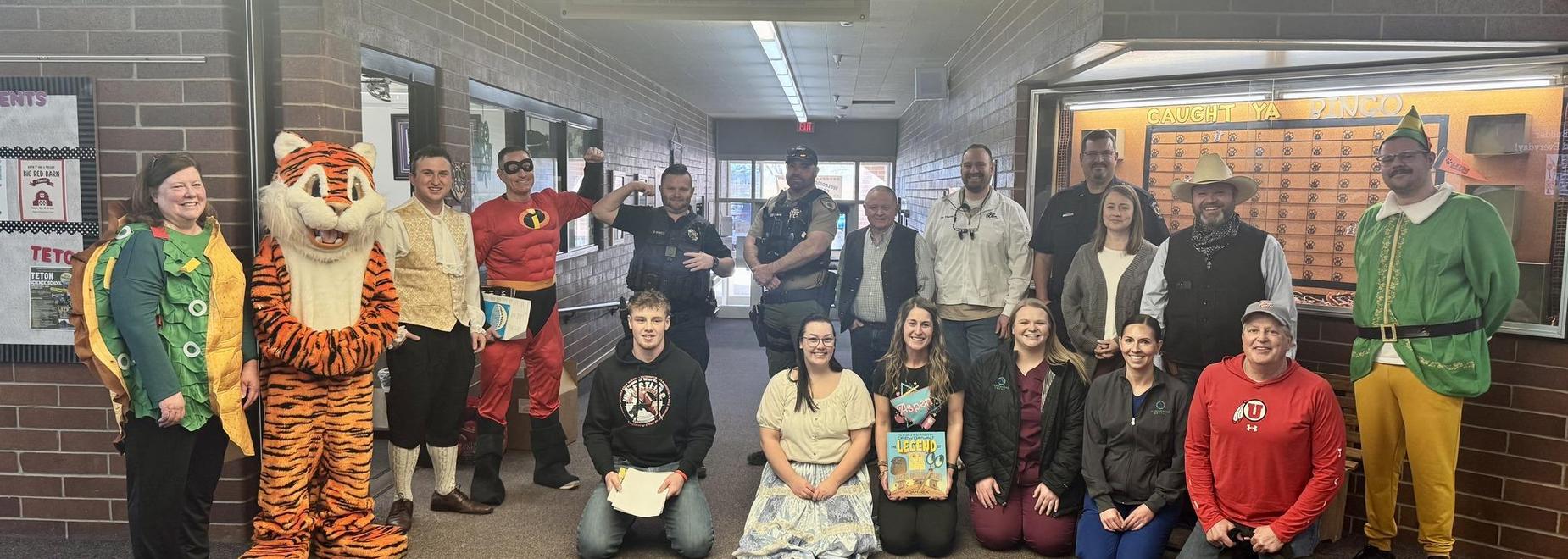 A group of people in costumes poses together in a hallway.