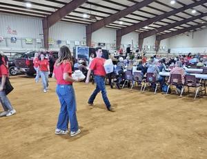 Multiple student council members delivering food plates to guests inside the agri center