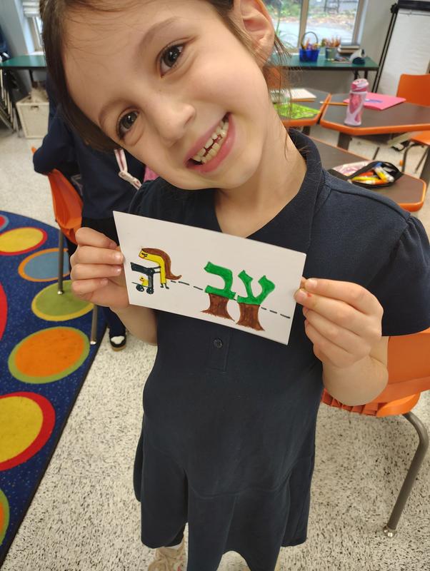 A student smiles while showing of the card for the word AVAR