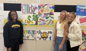 Three other girls stand beside their vocabulary word artwork