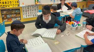 ninth grade boys help the kindergarten students review their hebrew reading skills.