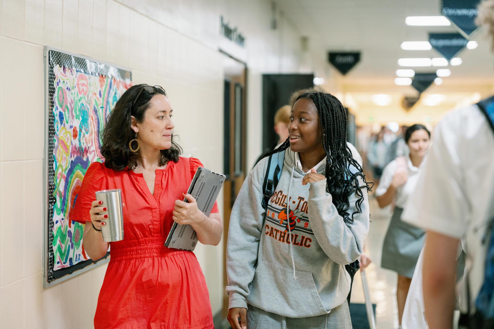 Student walking through campus alongside a school counselor.