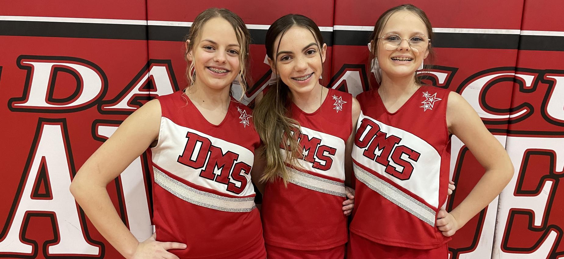 Cheerleaders stand in a gym.