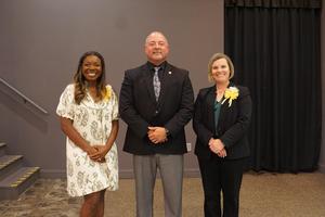 Three people standing together, smiling, at the WCS POY and TOY banquet