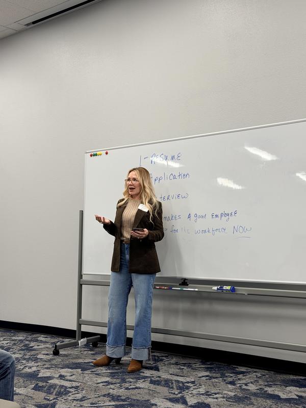 A woman stands by a whiteboard discussing job applications and interview tips.