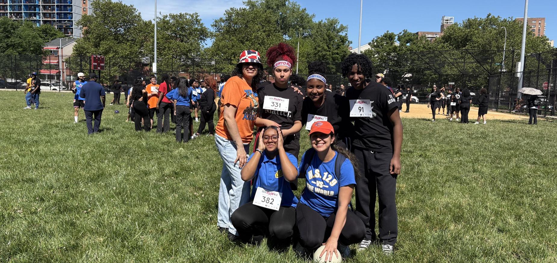 six people in a field with other people standing in the background