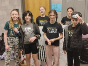 A team of elementary students posing together A team of elementary students in red headbands posing with certificates at the Odyssey of the Mind competition.