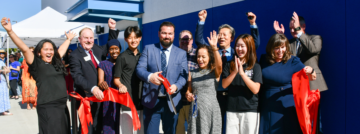 A diverse group of people celebrating at a ribbon-cutting ceremony.