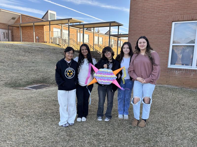 Girls standing with their pinata outside.
