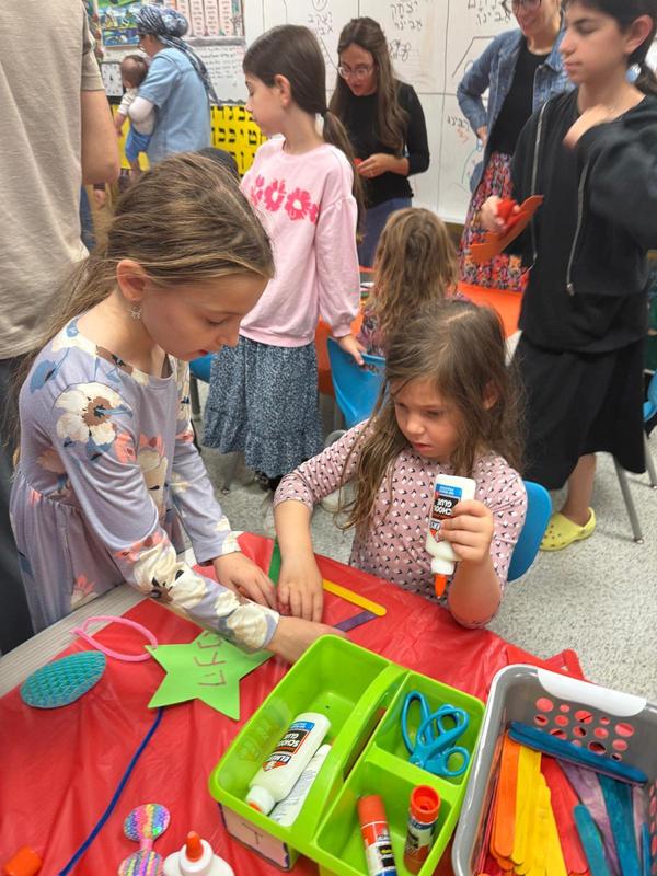 A kindergarten student and her older sister make a star to hang in the sukkah.