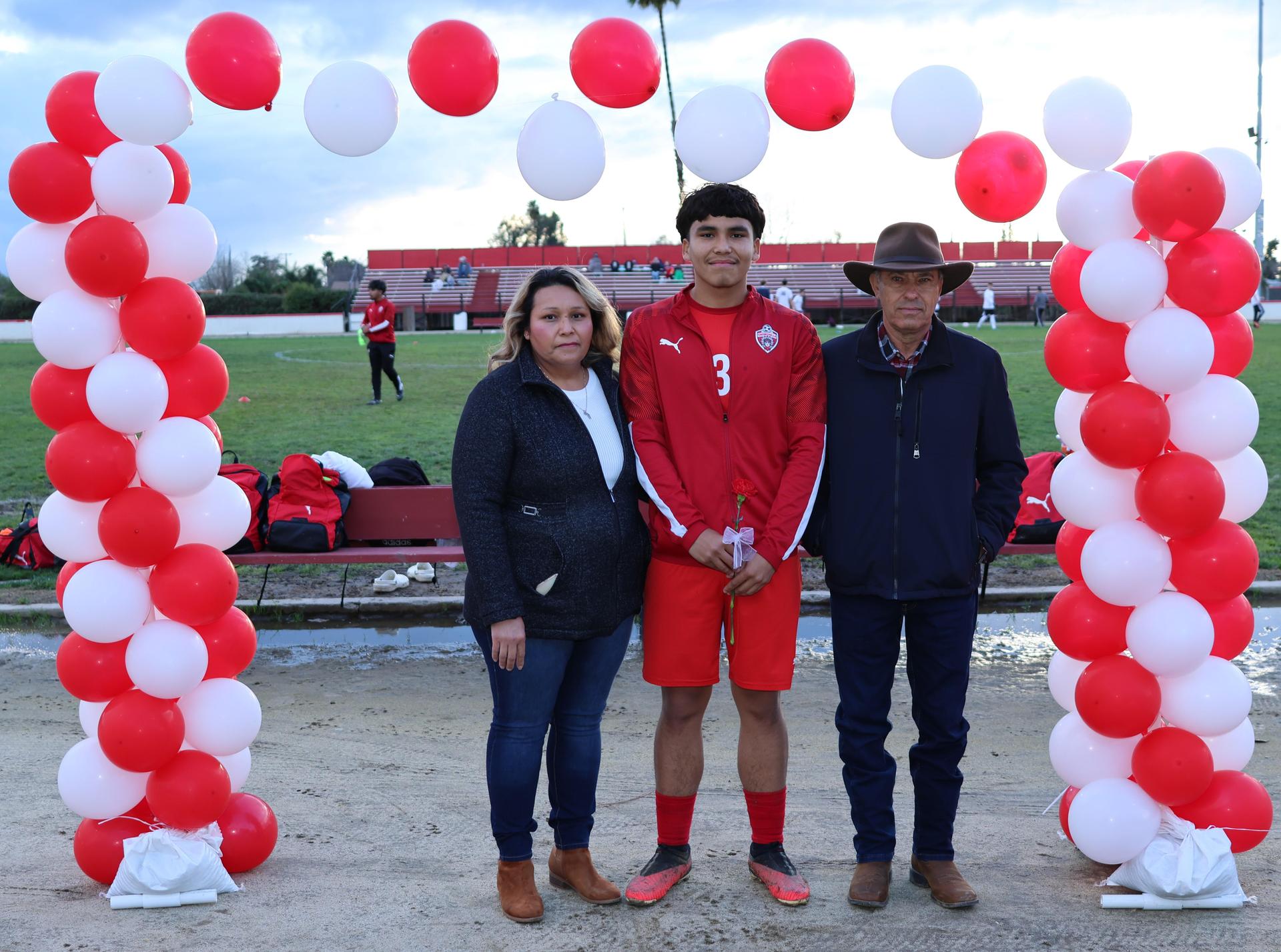 seniors and their escorts posing beneath a balloon arch