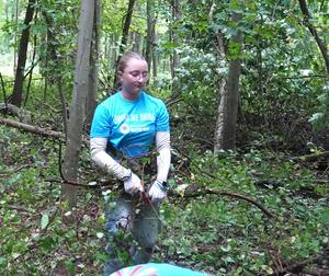 A student carries out brush from the woods.