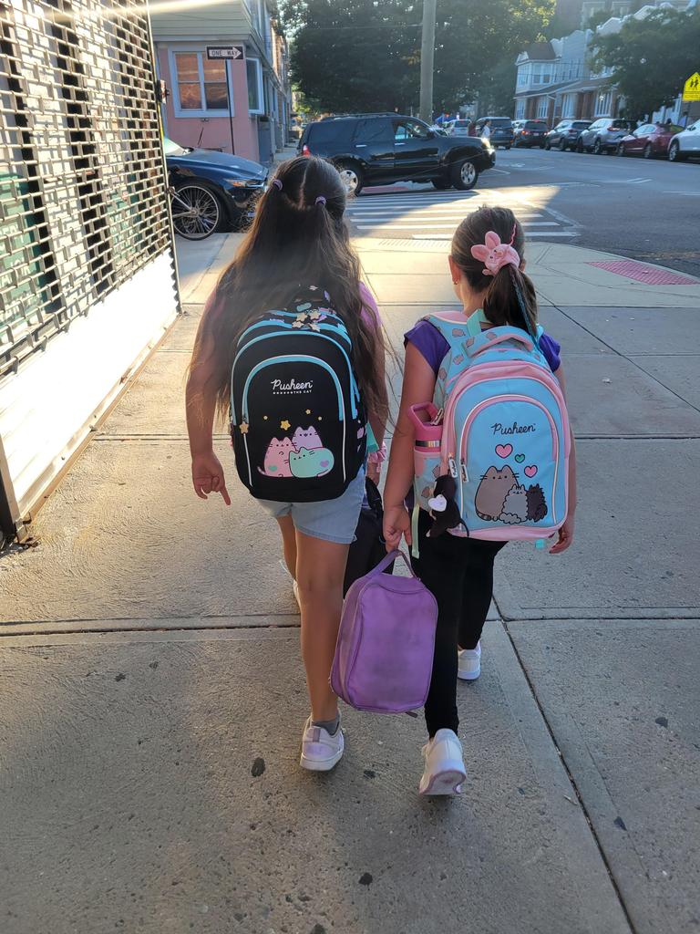 2 girls walking towards the1st day of school with backpacks