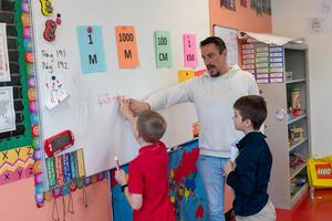 A teacher and two students work together at a whiteboard at Arco Iris Spanish Immersion School.