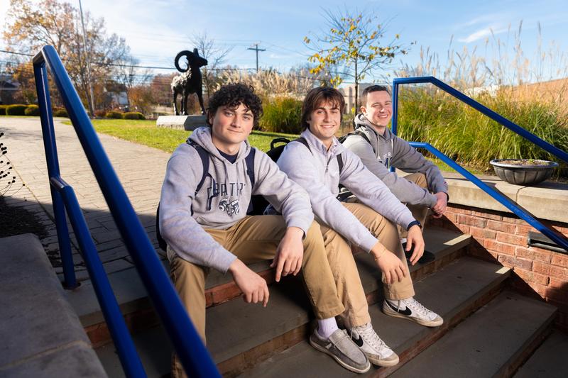 Three young men smiling on campus