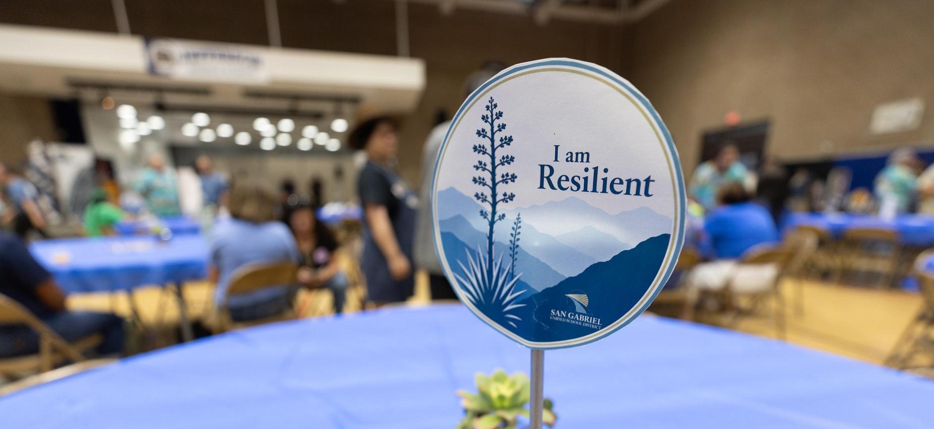 A table setting featuring a sign that reads 'I am Resilient' at an event.