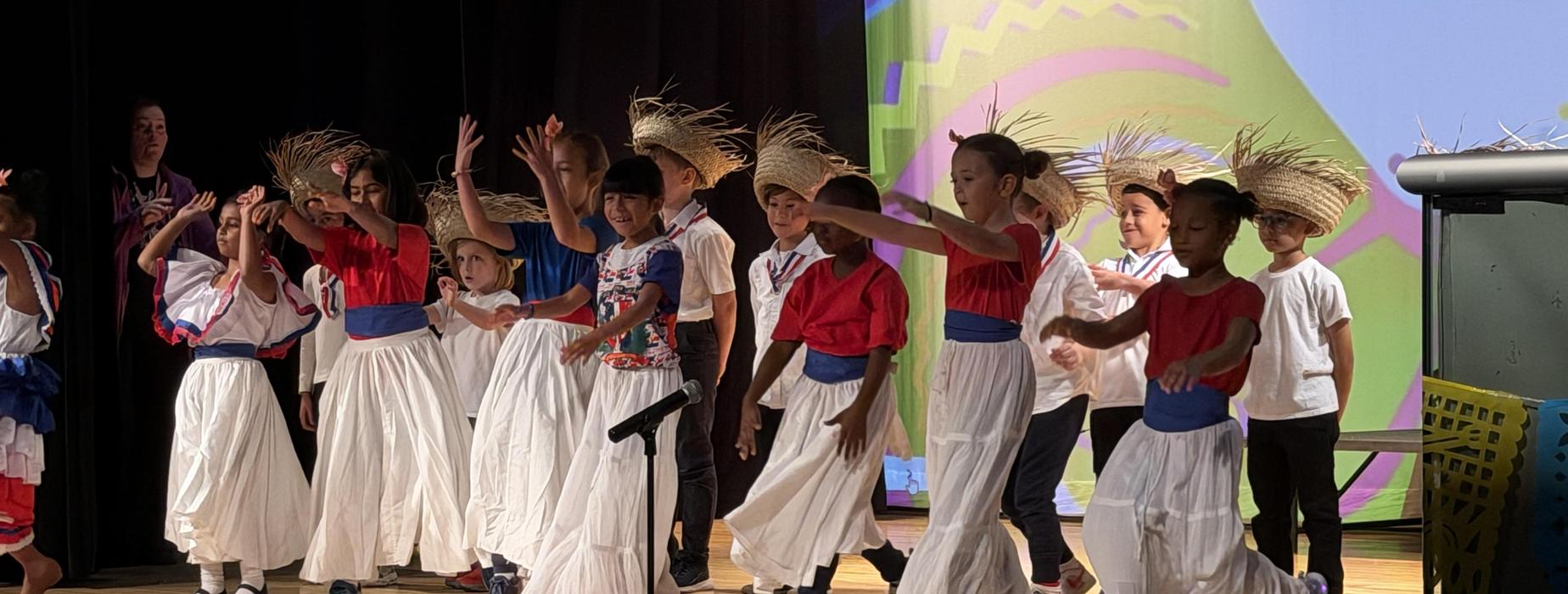 Children in traditional attire performing on stage with dance moves.