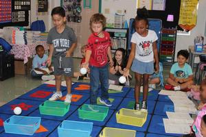 Students throw balls into baskets during an experiment on force