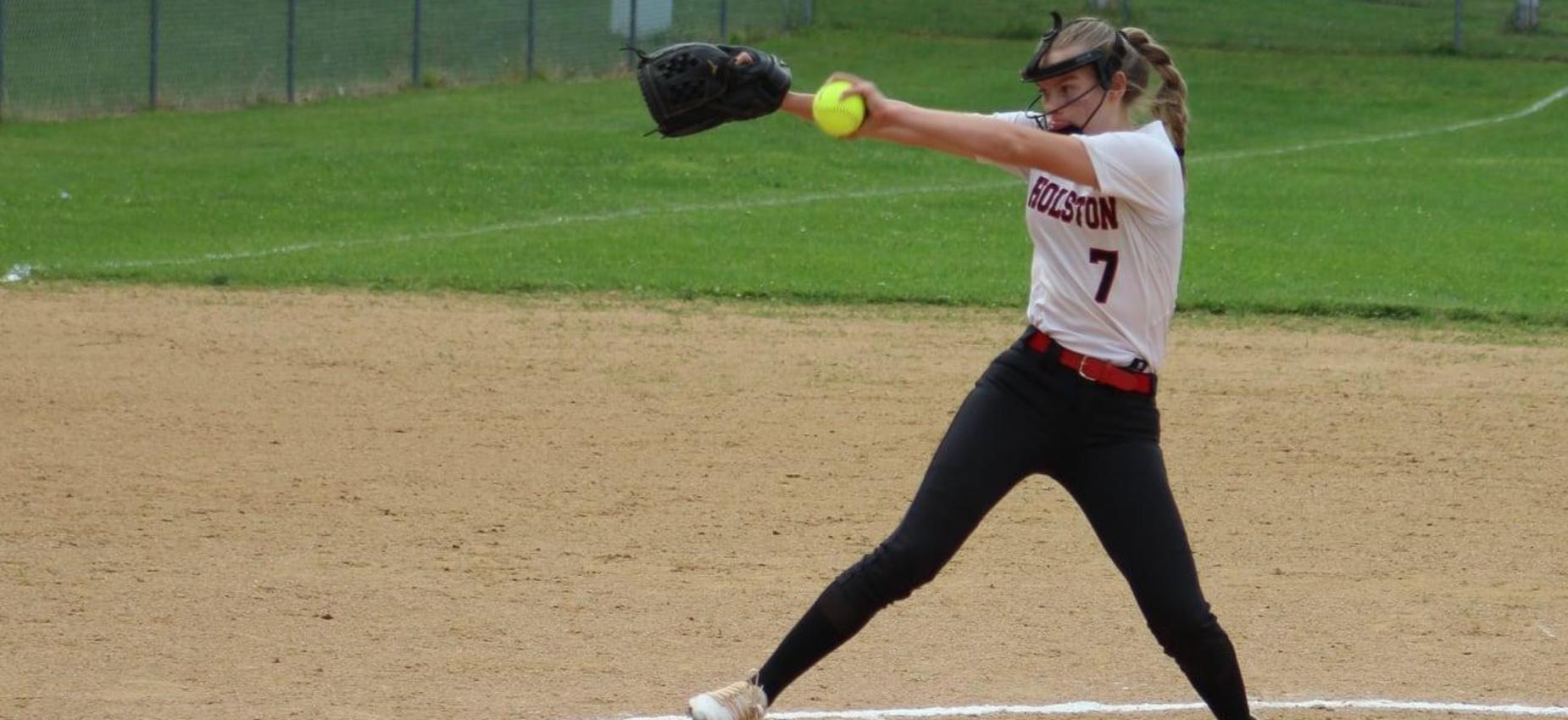 A softball player pitches the ball.