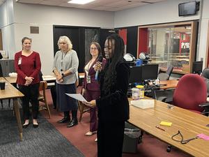 Student holding microphone welcoming the group