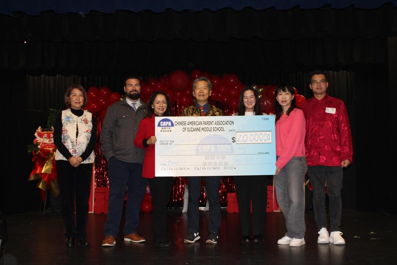 Group of people presenting a large check at a celebration event.