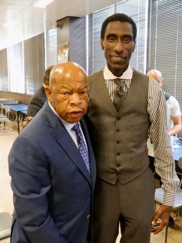 John Lewis and a man posing together in a venue setting.