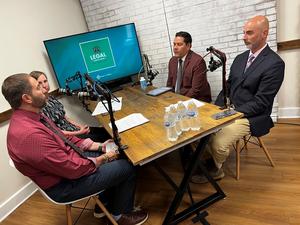 four adults sit around a podcast table talking into microphones