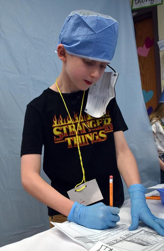 A student writes during a classroom activity while wearing gloves.