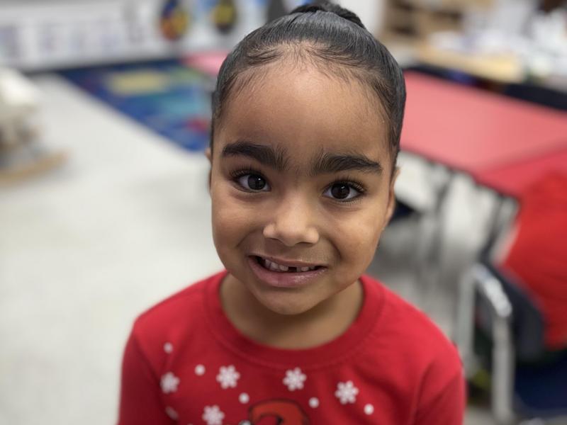 Smiling boy in a Christmas sweater holding a bowl of food.