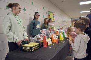four girls standing behind a table covered in gift baskets