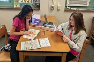 Sixth-graders Donna Scarpine and Emma Novak relax in the library with some of the new novels