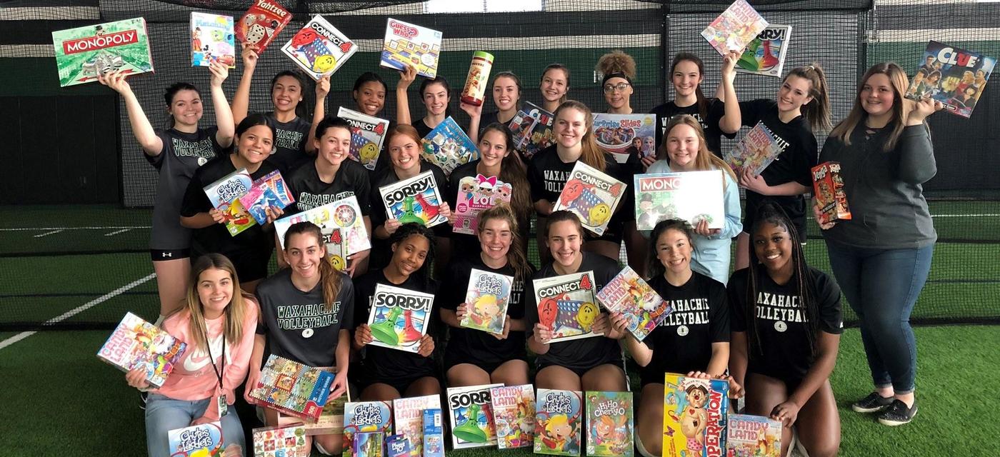 Volleyball players with games donated for Toy Drive