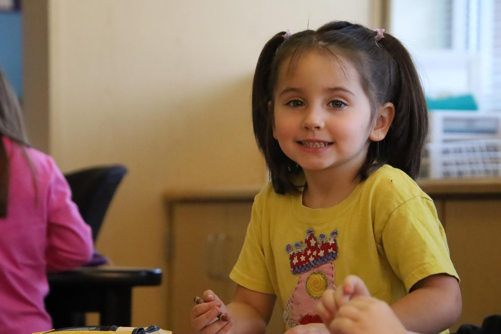 elementary school girl smiling for the camera in a classroom