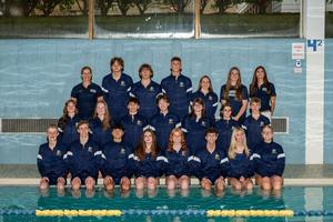 swim team in warm up jackets on side of pool