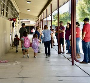 Parents and students walk together along a school hallway on the first day of classes