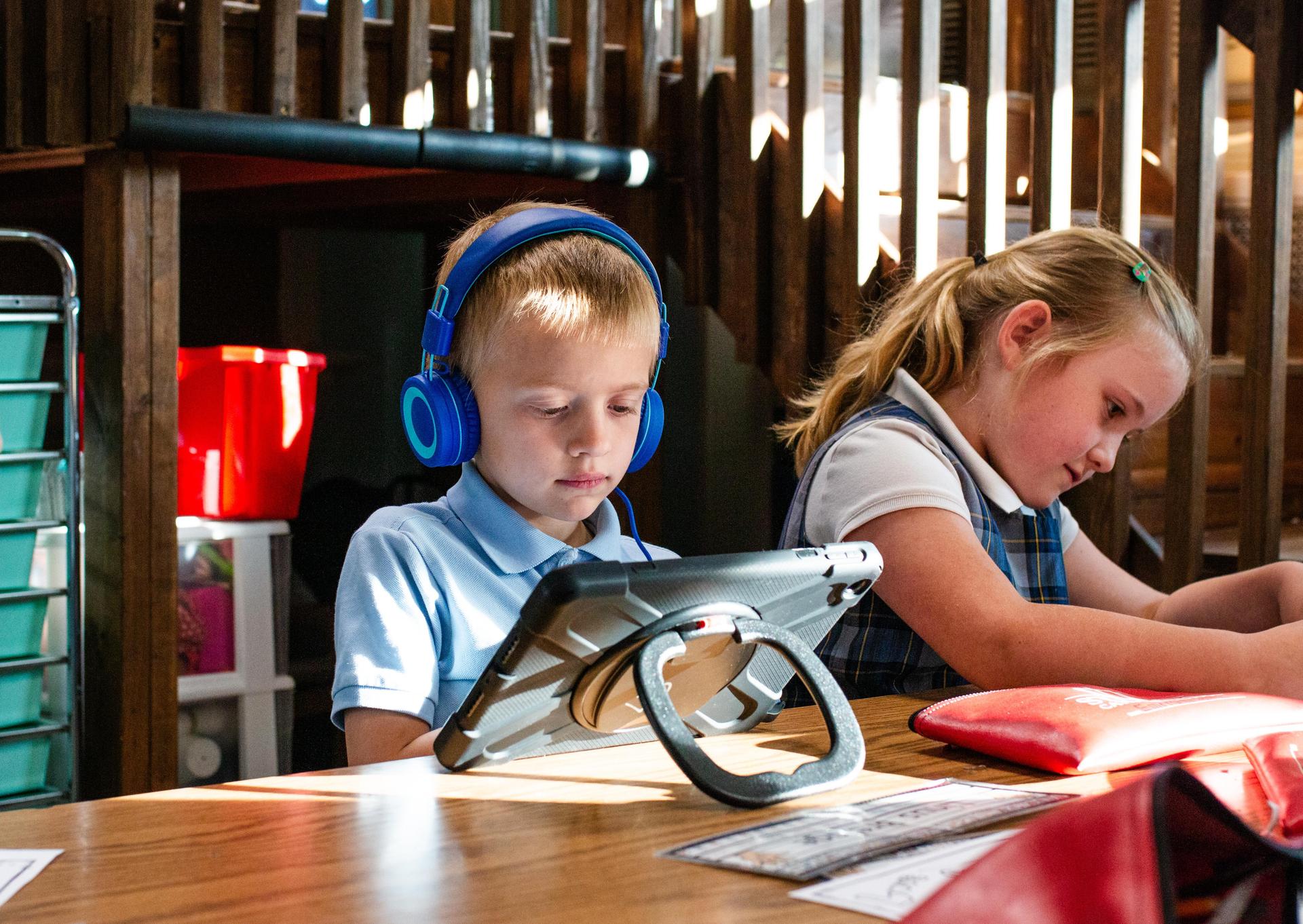 Student wearing headphones and working on iPad.