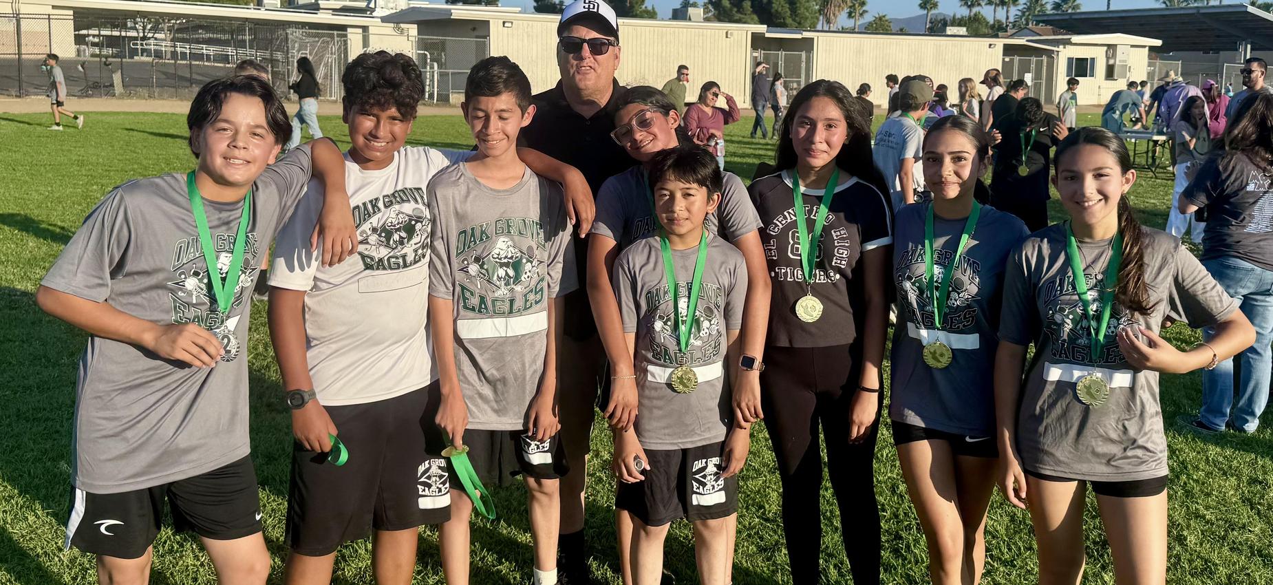 OGMS Cross Country students with medals on a sports field.