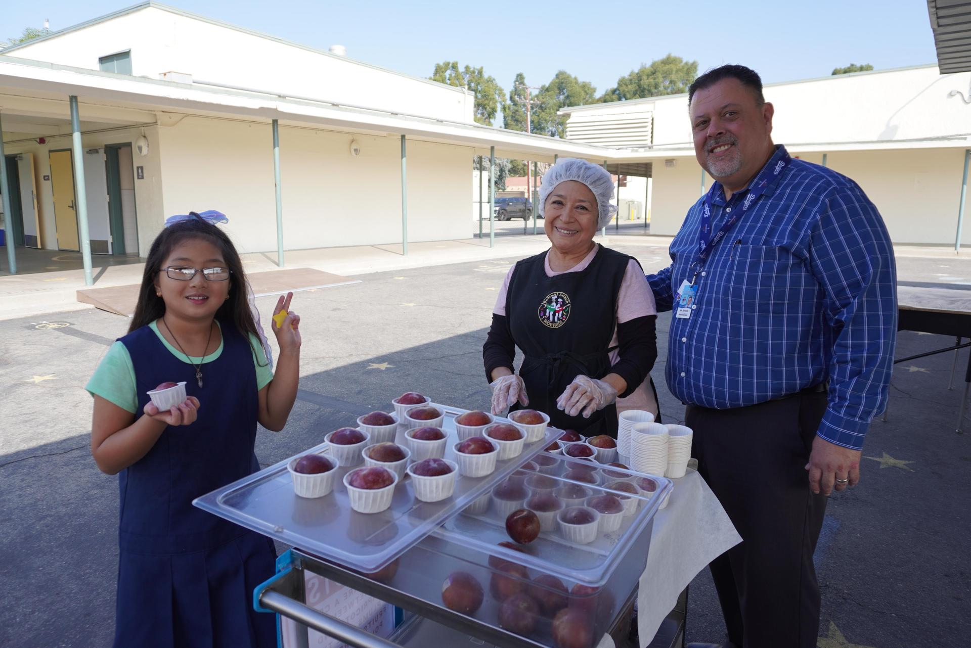 Students trying pluot (a hyrbid fruit that is part plum and part apricot).