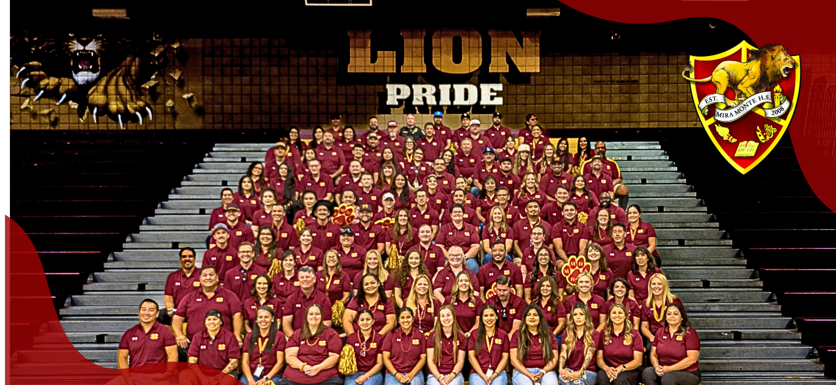 Large group of people in matching maroon shirts sitting on bleachers, displaying school spirit.