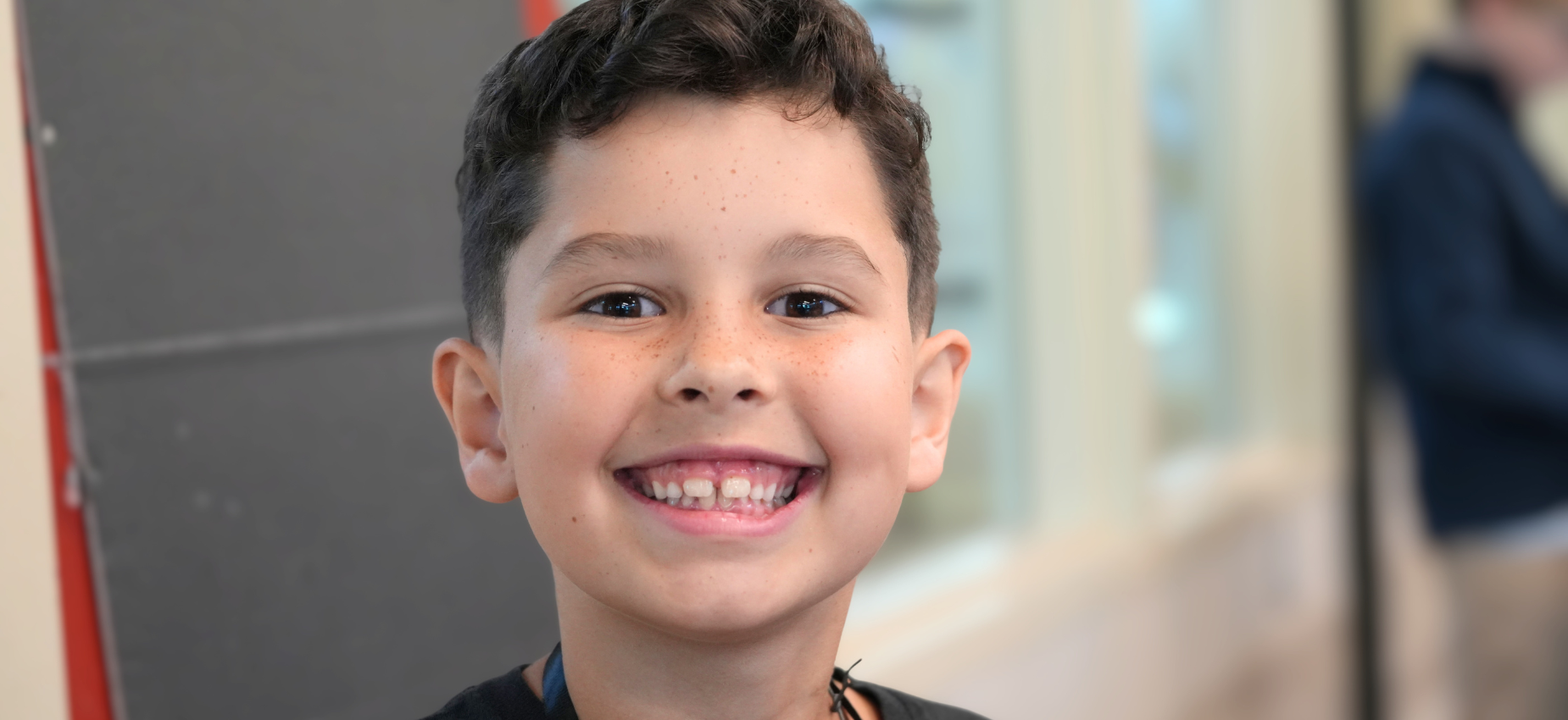 Close-up of a smiling boy with freckles.