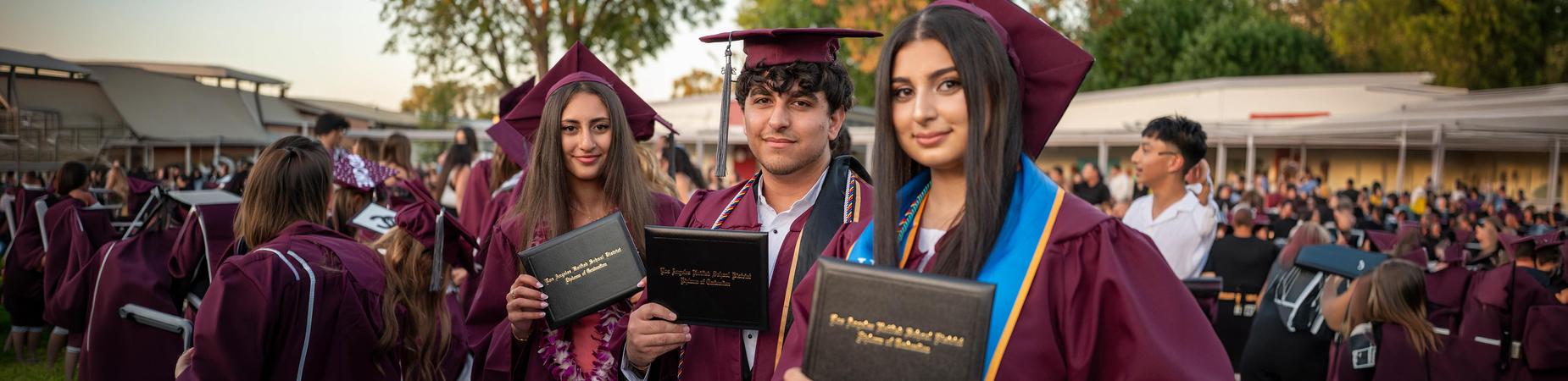 Three graduates with diplomas
